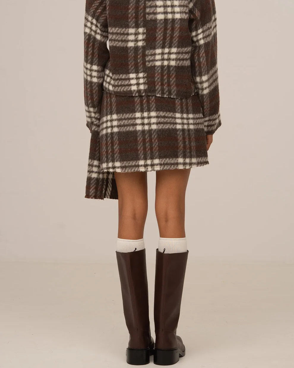 Brown plaid mini skirt by māre, featuring a stylish short length and classic plaid pattern, shown worn barefoot.
