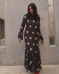 Woman in a polka dot dress standing in front of a concrete wall.