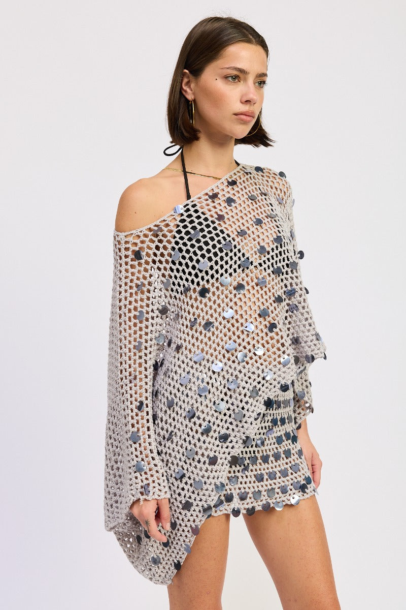 Pale blue silver poncho top by māre hanging on a display, showcasing its lightweight fabric and relaxed fit.